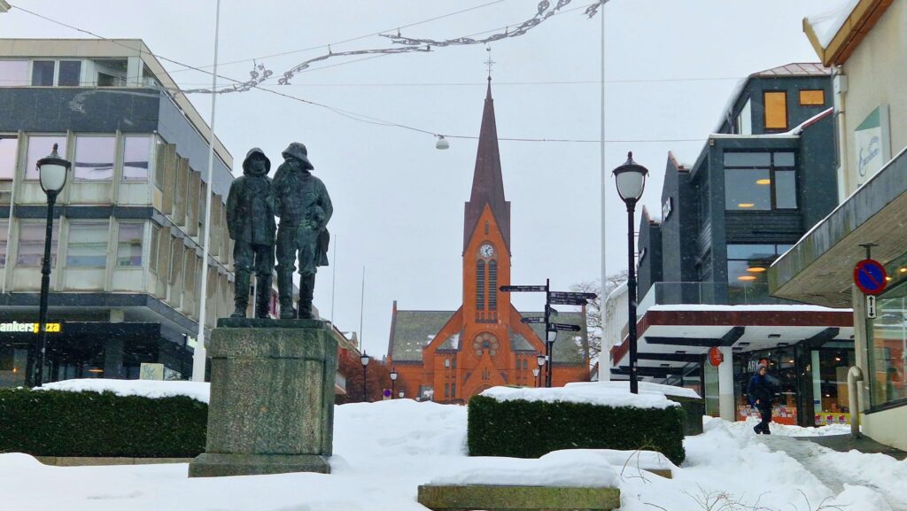 Haugesund na weekend Posąg Fiskerne, a w tle Vår Frelsers Kirke (Kościół Naszego Zbawiciela) w Haugesund